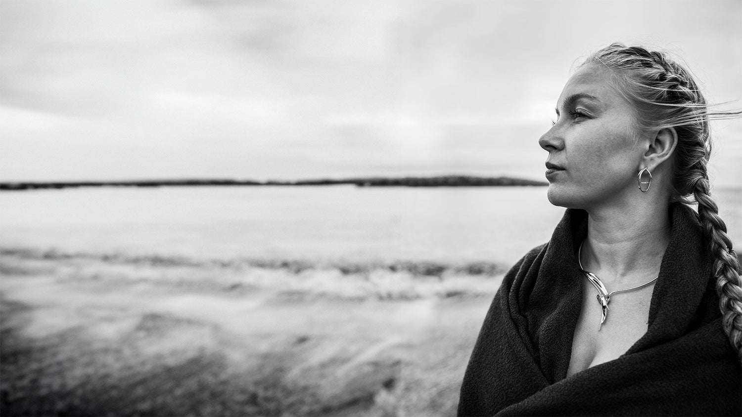 Kvinna vid havet iörd smycken ur Guldvivas Stormskärs Maja-kollektion