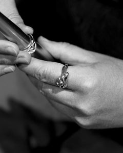 Close-up of hands fitting a silver ring onto a finger during craftsmanship