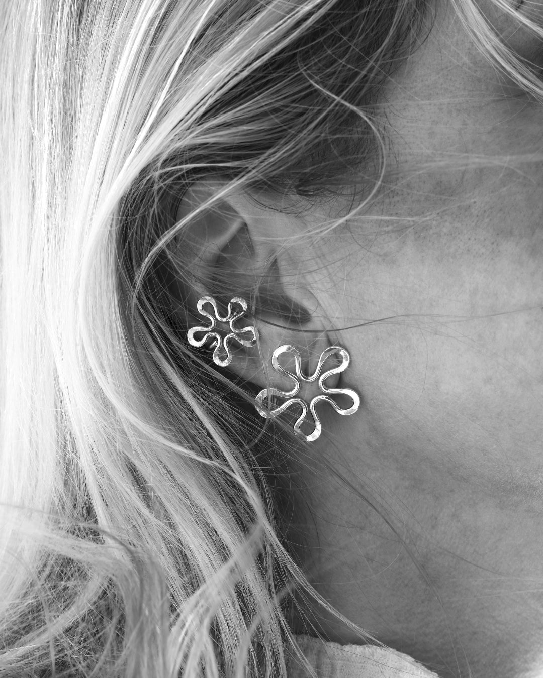 Pair of Blomman sterling silver flower ear cuffs worn on the ear, one large and one small