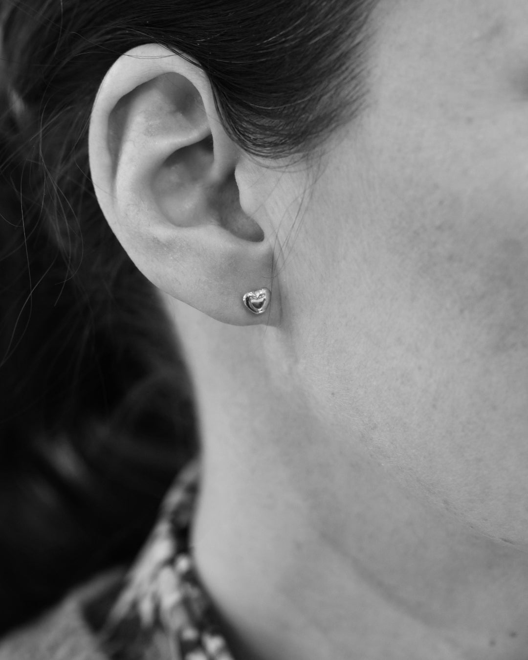 Litet hjärtformat stiftörhänge i sterlingsilver på örsnibben
