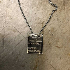 Rectangular silver ID bricka pendant with engraved numbers and name on a chain