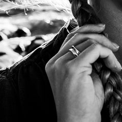 Black and white photo of a person wearing a minimalist sterling silver STORMSKÄRS MAJA ring near a braided hairstyle.