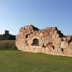 Stone wall of Bomarsund fortress built from large granite blocks with a small arched doorway on a grassy field