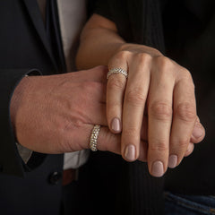 Two hands wearing matching silver rings with a golf ball pattern