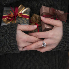 Handen i en mörk stickad tröja bär en handgjord ring i 925 sterling silver med fyra potatisformade delar
