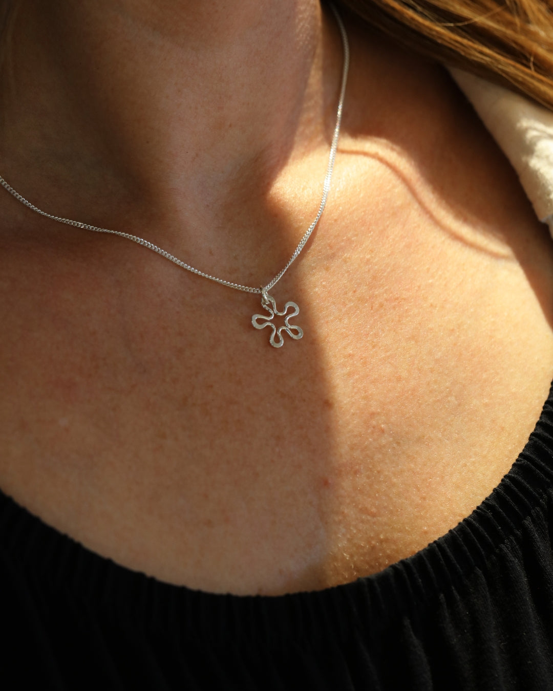 Blomman™ XS necklace in 925 sterling silver with handmade flower design on Curb chain, worn around the neck.